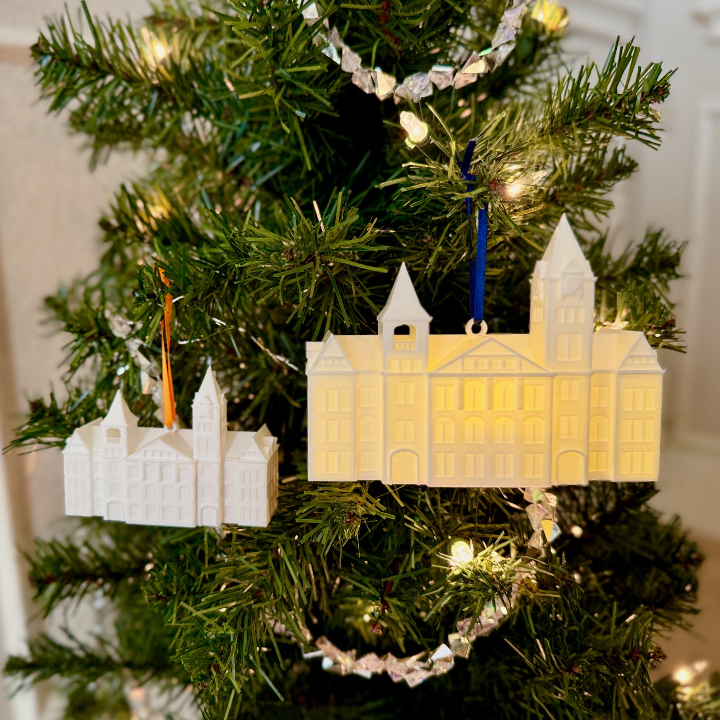 Two Auburn ornaments, shown side by side on a Christmas tree, designed as a replica of the Samford Hall building.