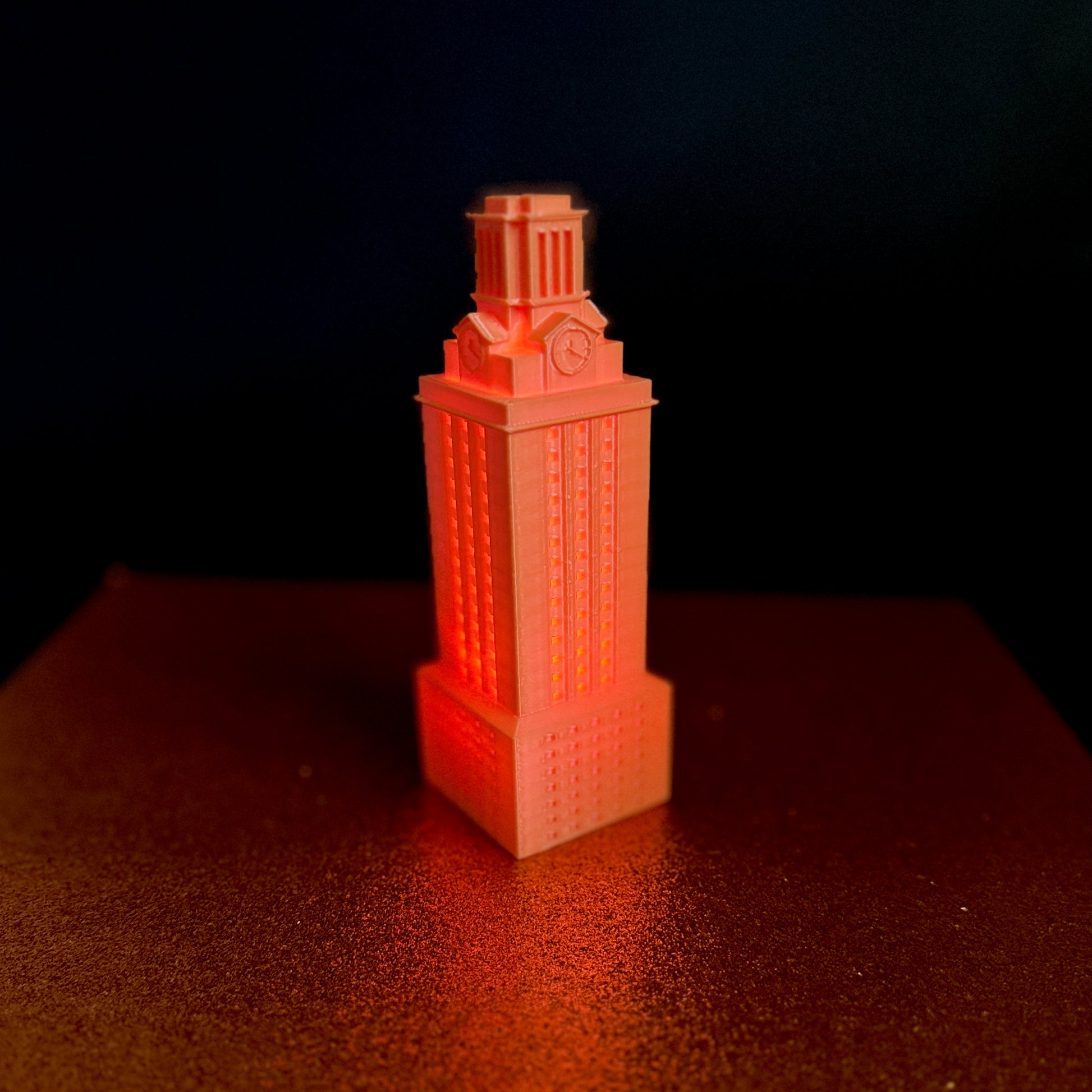 The UT Austin figurine of the UT Tower, shown in orange and used as a University of Texas  gift or Texas Longhorns decor.