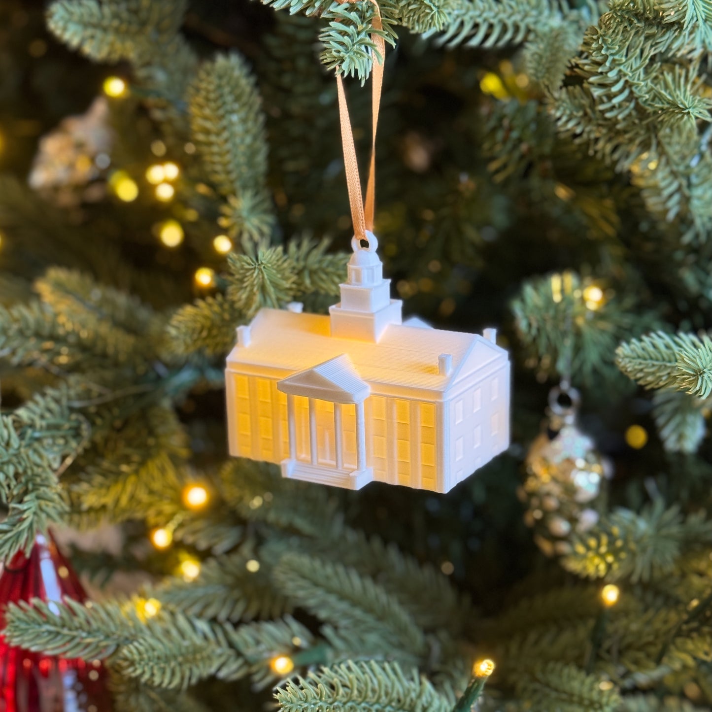 Side view of the lighted University of Iowa ornament, shown on a Christmas tree.