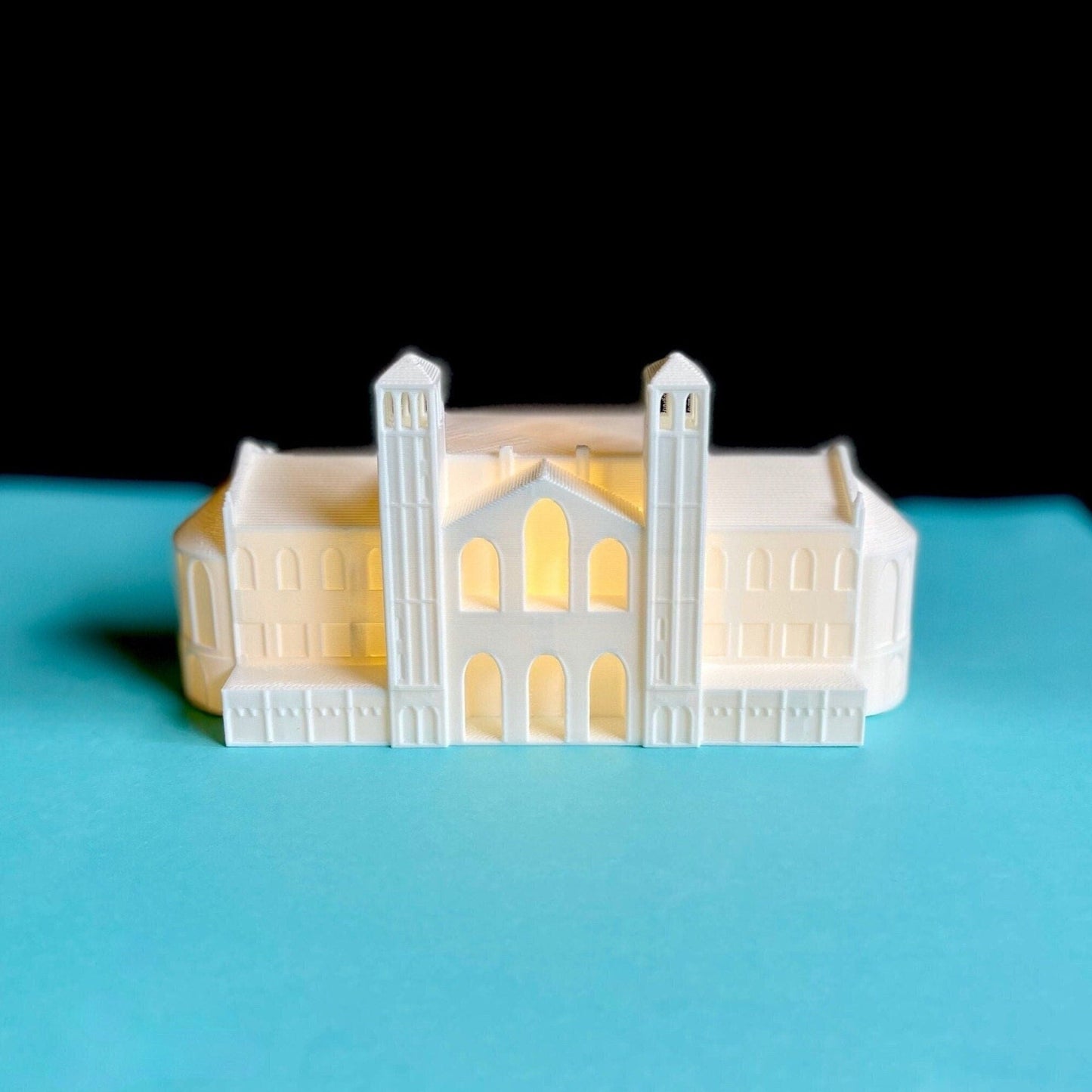 The lighted UCLA figurine of Royce Hall, shown against a blue background.