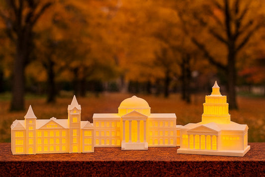 3D-printed LED lighted campus building ornaments glowing on a fall day with autumn leaves in the background.
