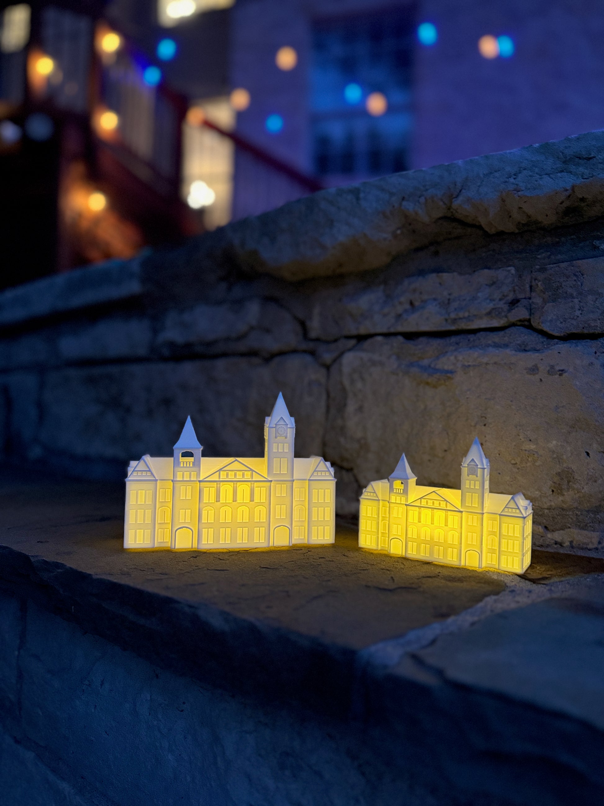 Two Auburn University keepsake figurines (Samford Hall lights) shown at an outdoor wedding with twinkle lights.