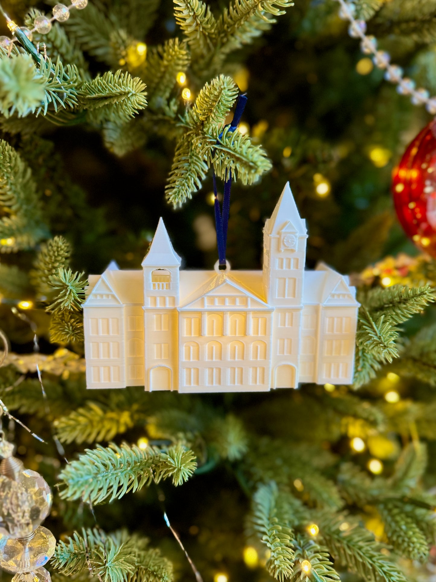 Front view of the LED lighted Samford Hall ornament, shown on an Auburn tree.