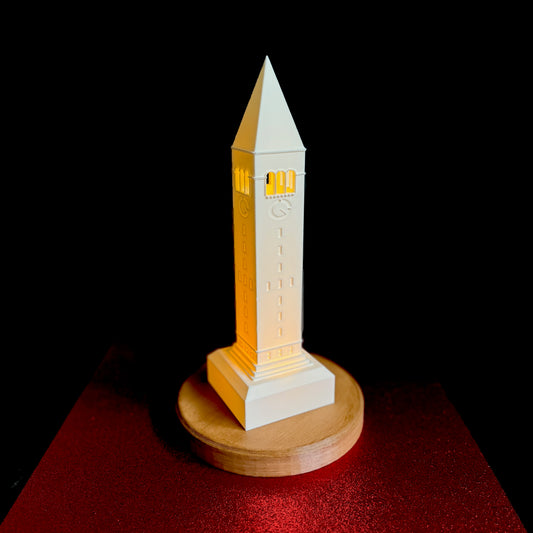 The Cornell lamp, shown against a red background and designed as a replica of the McGraw Tower campus building.