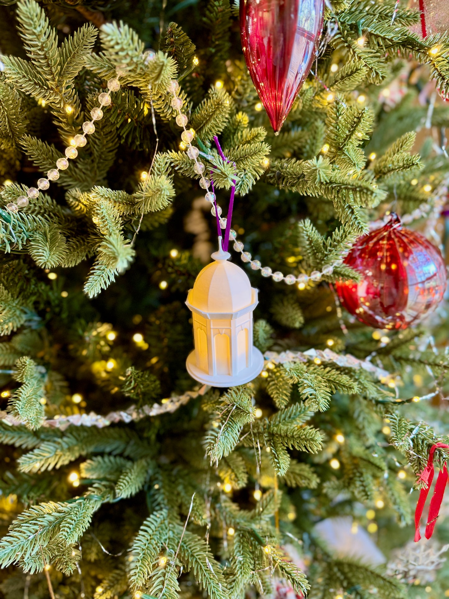 The ECU alumni ornament designed as the Cupola, shown with an LED light on a Christmas tree.