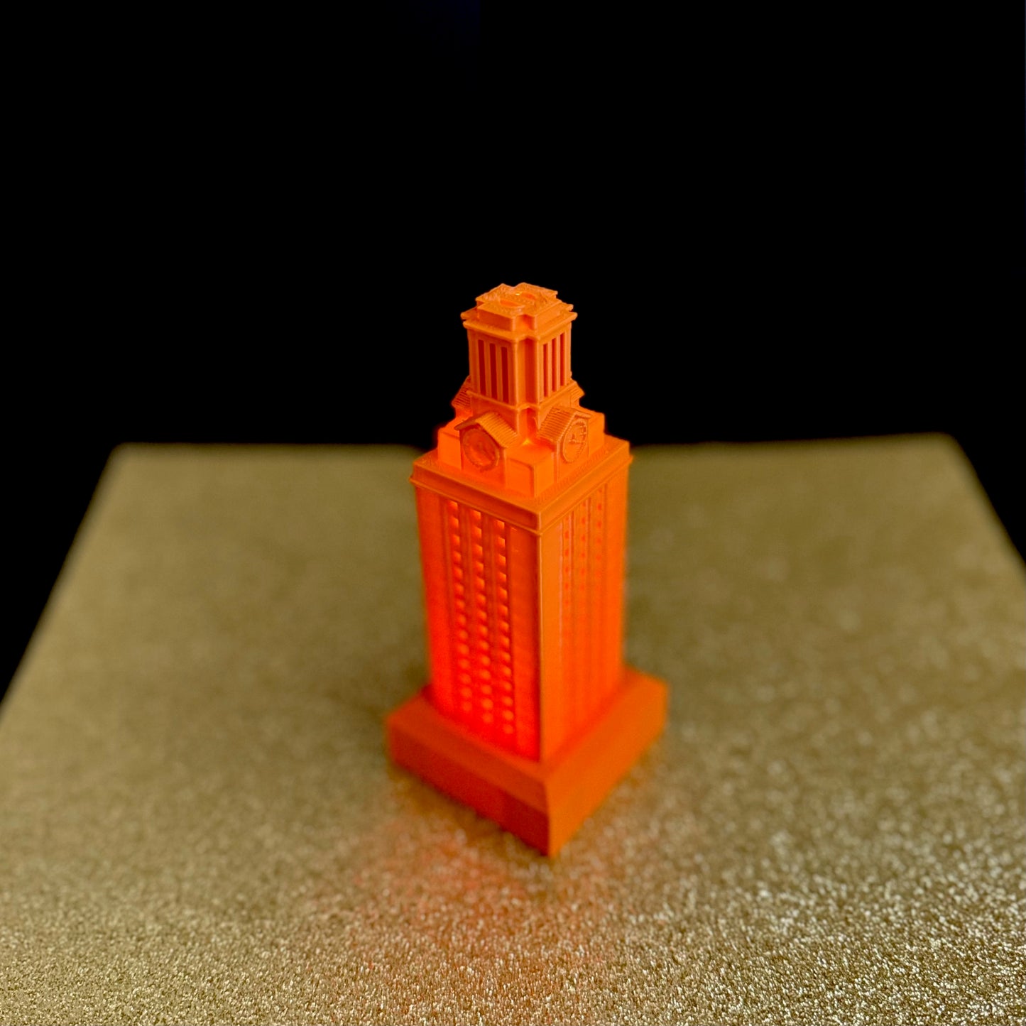 The UT campus figurine, shown against a gold background.