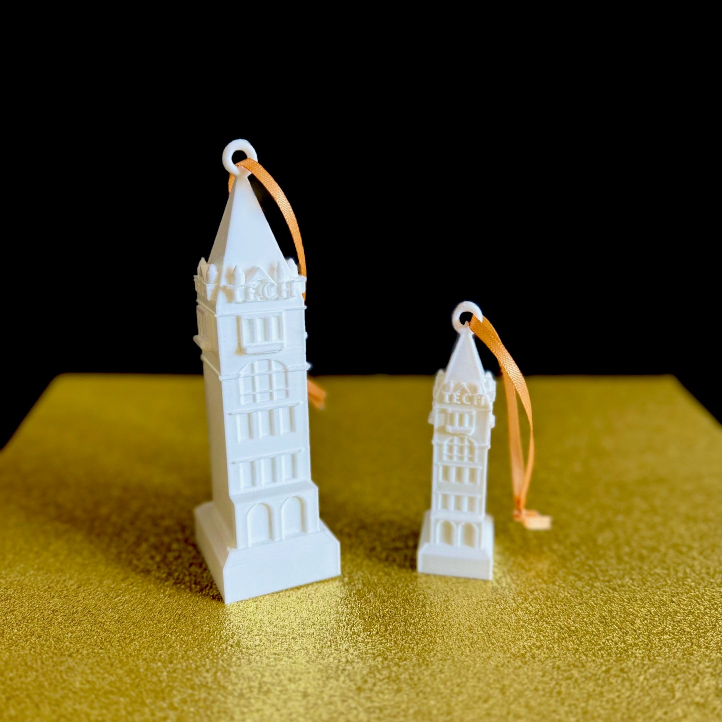 The 3D printed Georgia Tech ornaments, shown against a gold backdrop.