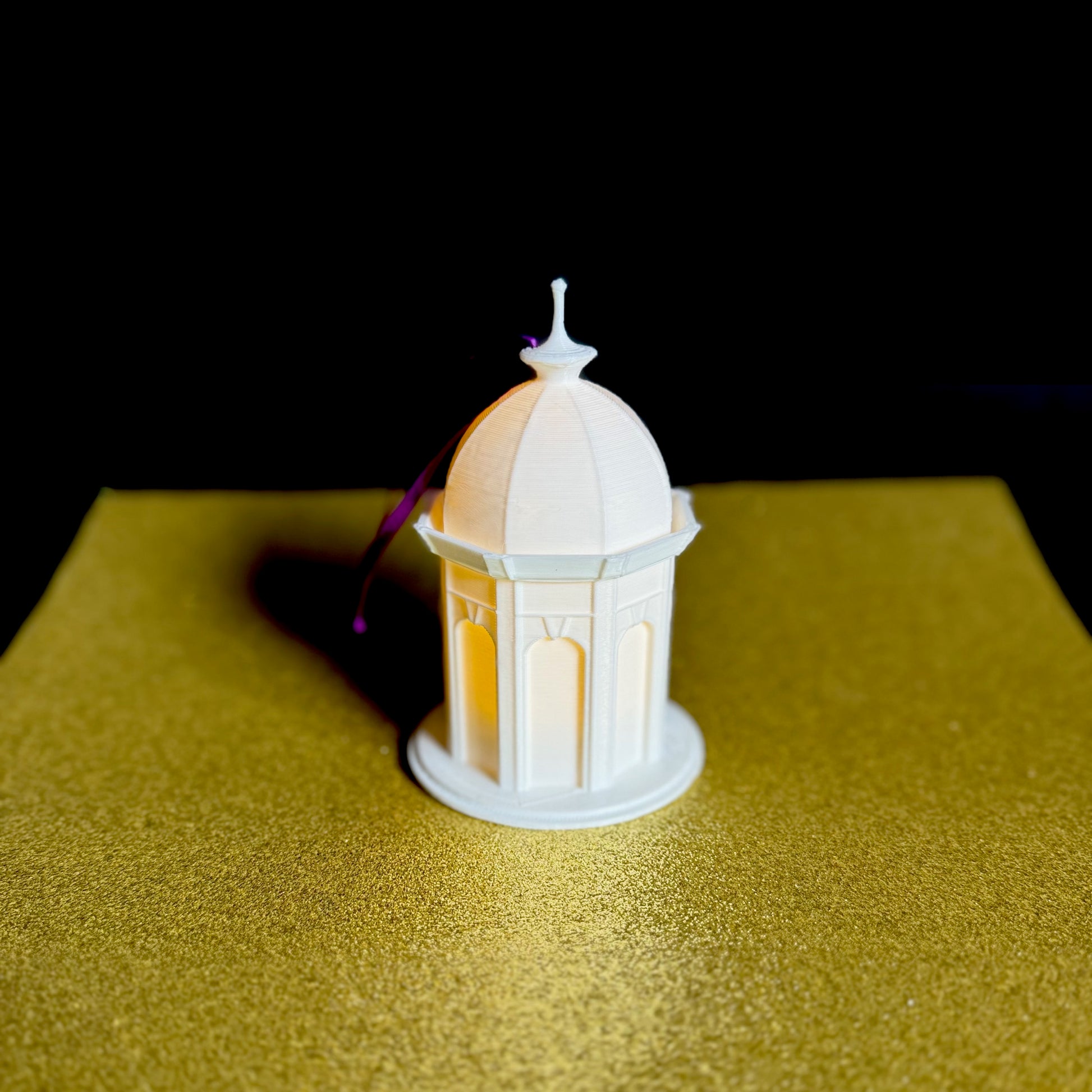 The lighted East Carolina Christmas ornament, designed as the ECU Cupola and shown against a gold background.