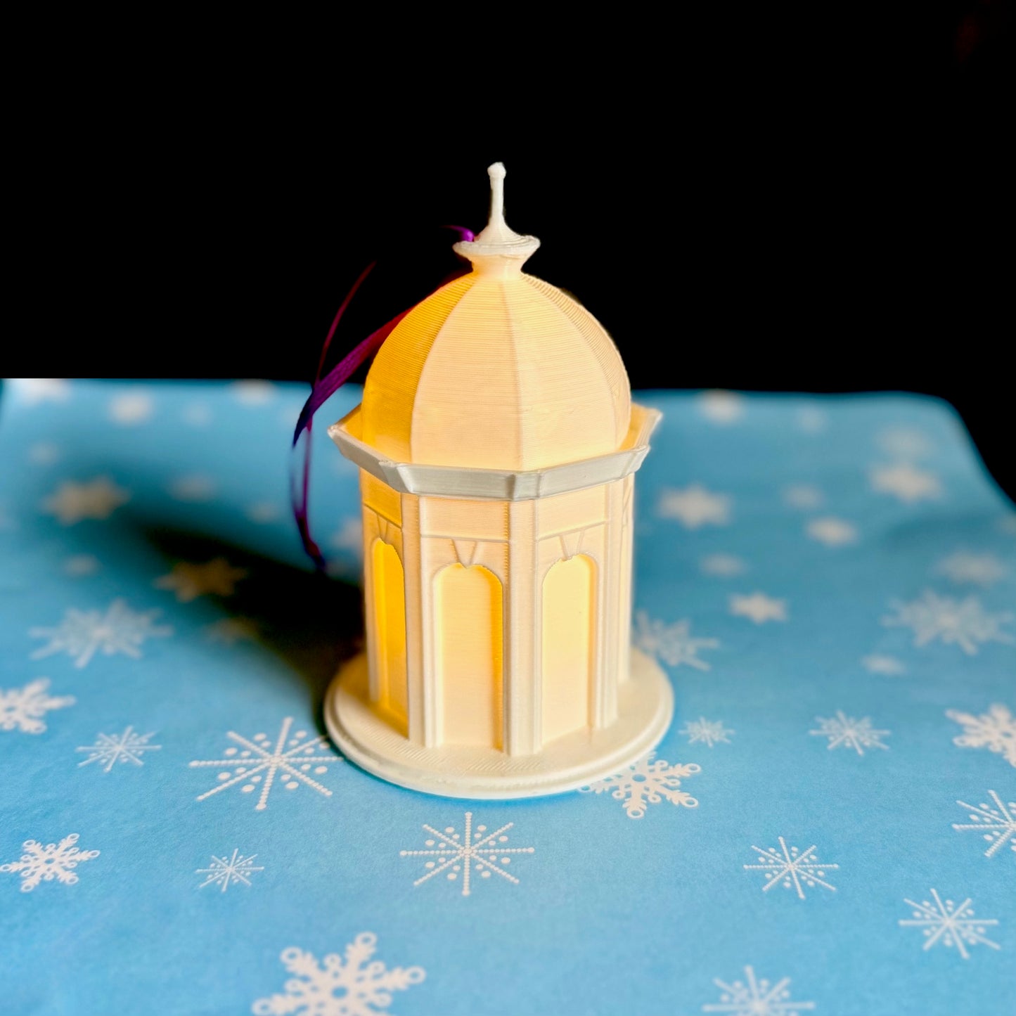 The lighted ECU ornament, shown against a blue holiday background.