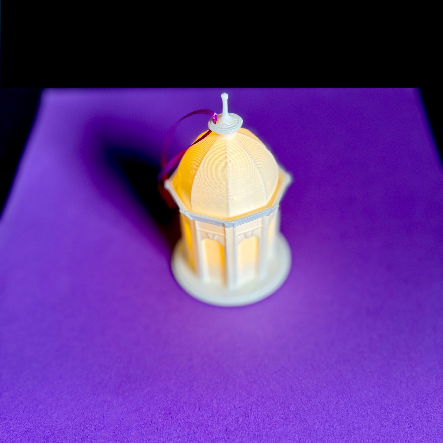 The lighted East Carolina Cupola ornament, shown on a purple background.