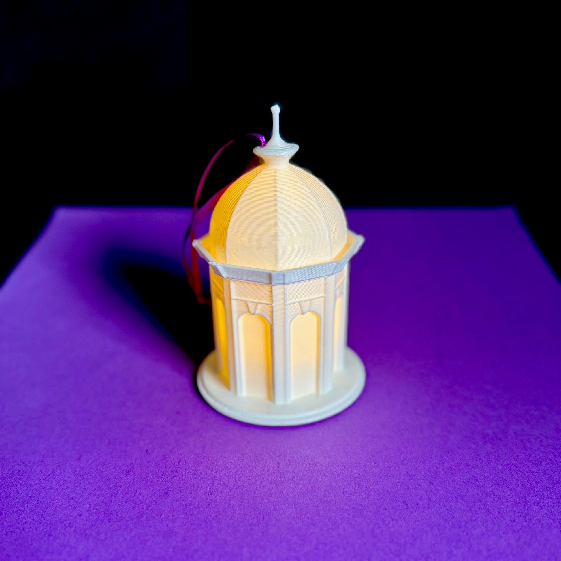 The ECU Cupola ornament with a light, shown against a purple background.