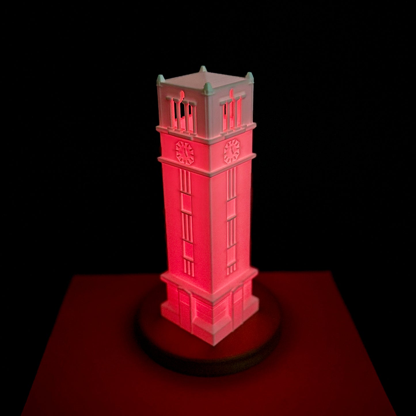 The NC State Tower light, shown against a red and black NCSU background.