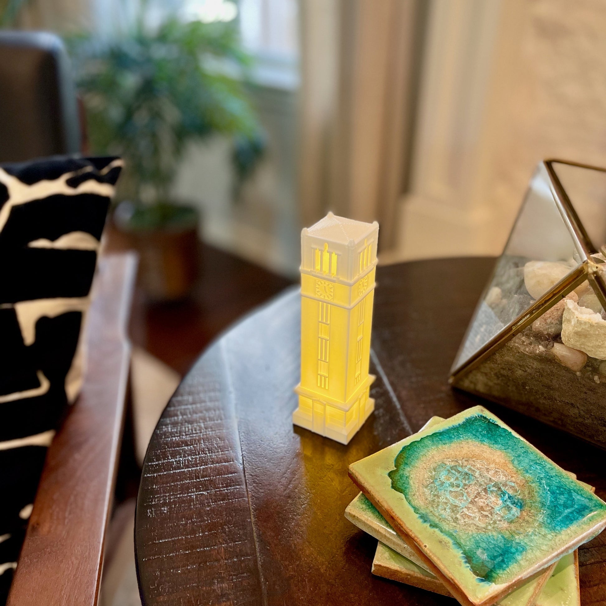 The NC State Bell Tower figurine, shown on a living room side table.