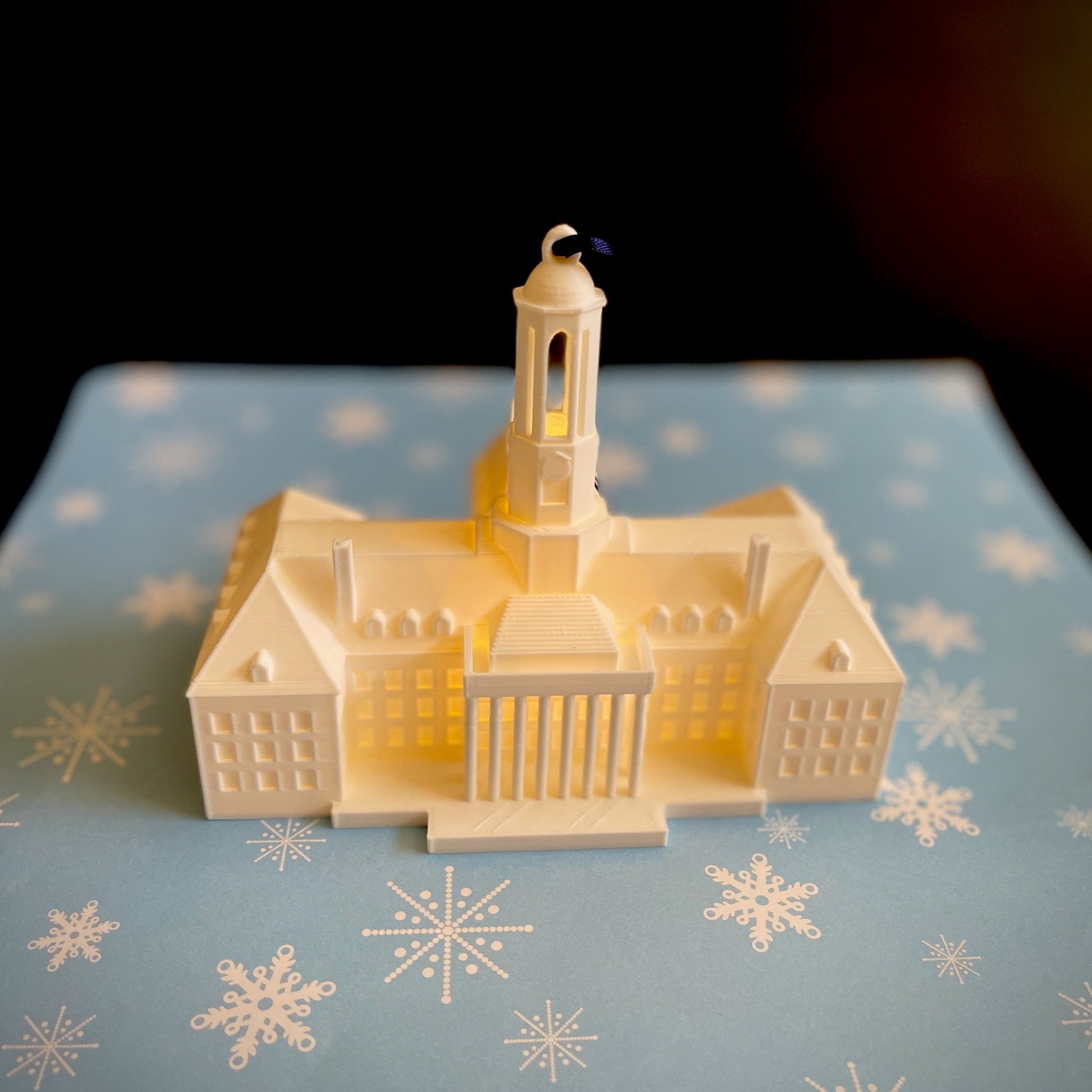 Front view of the Penn State ornament light, shown on a blue holiday background.