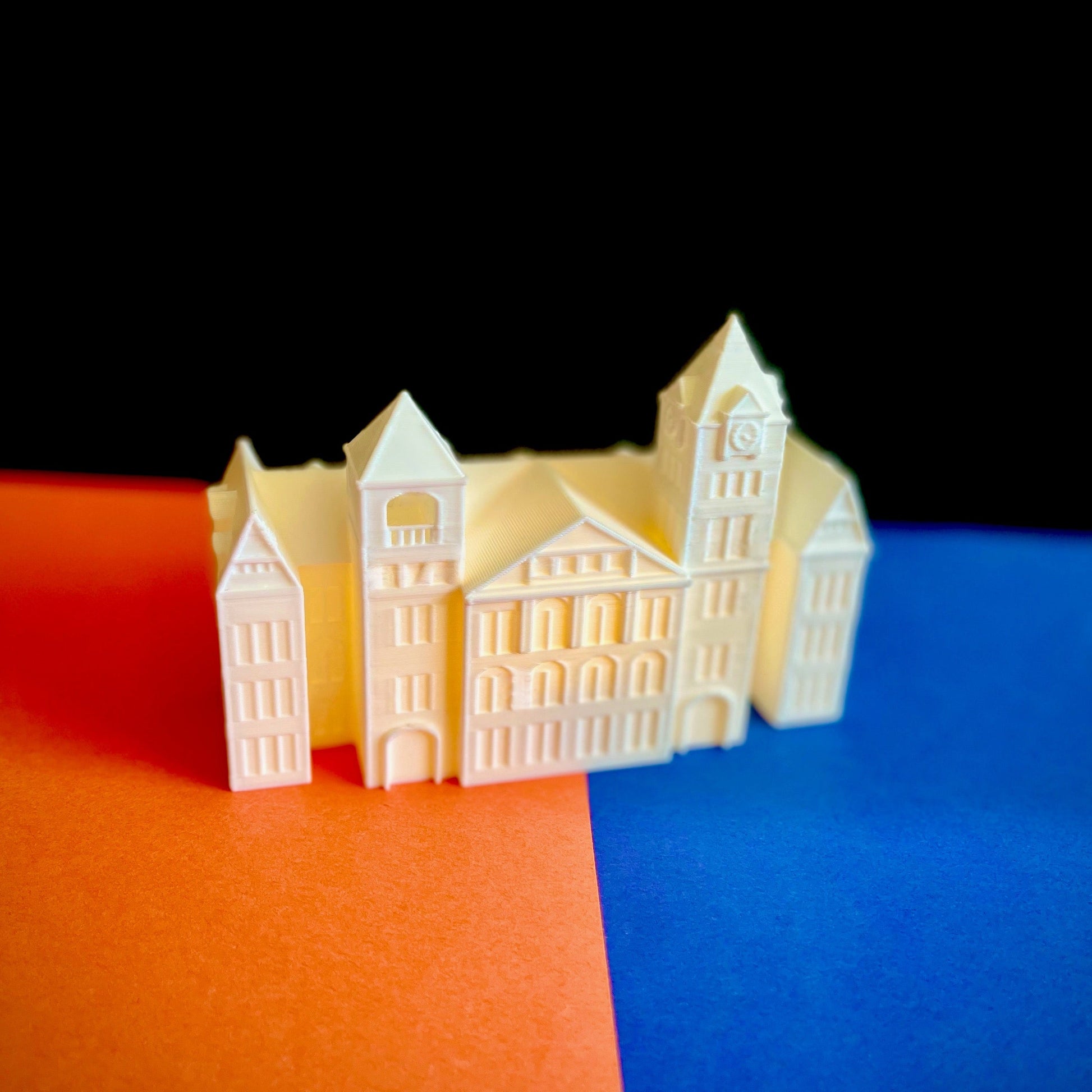 The lighted Samford Hall figurine, shown against an orange and blue background.