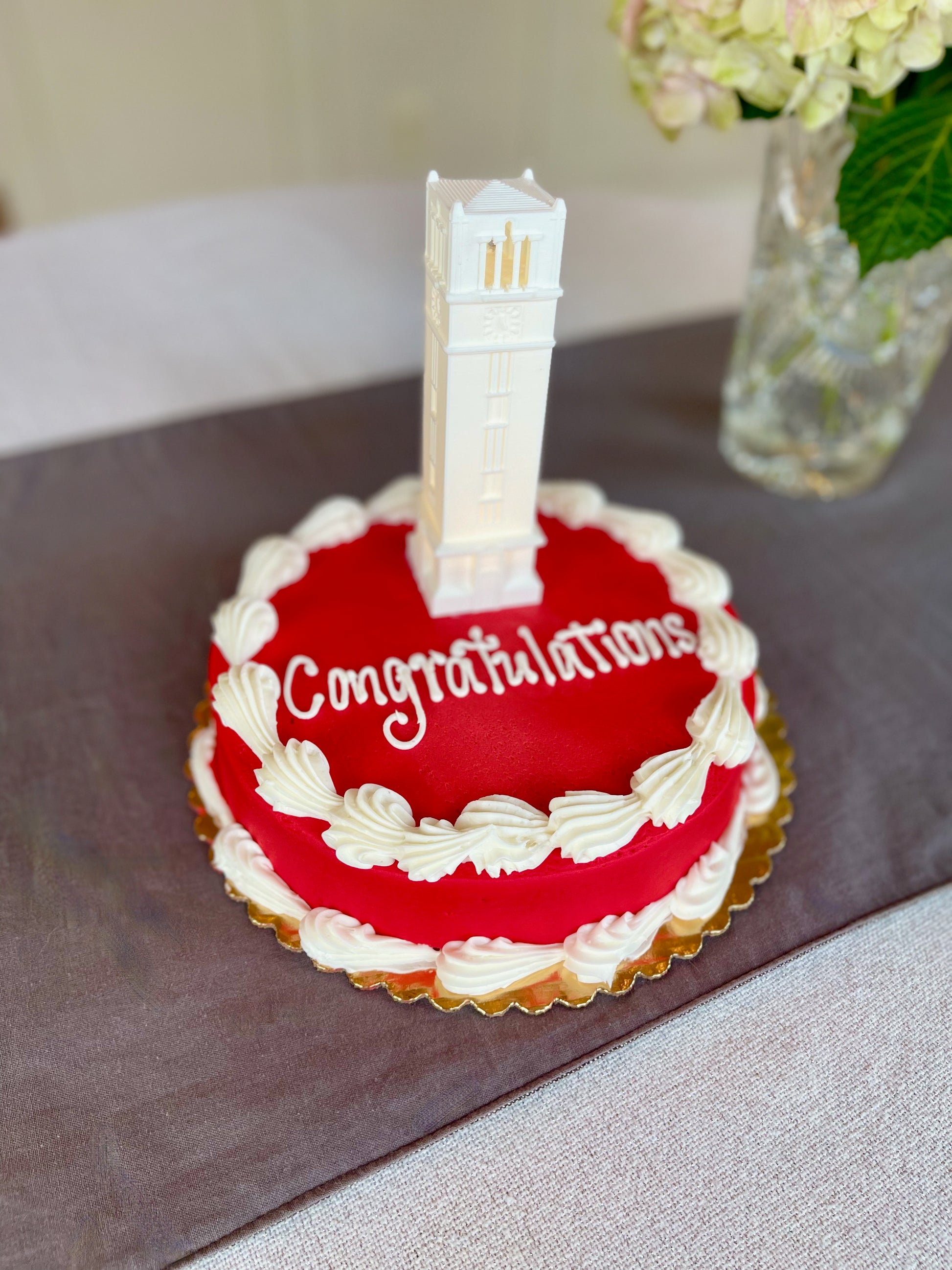 Closeup view of the NC State cake topper, displayed on a red NC State graduation cake.