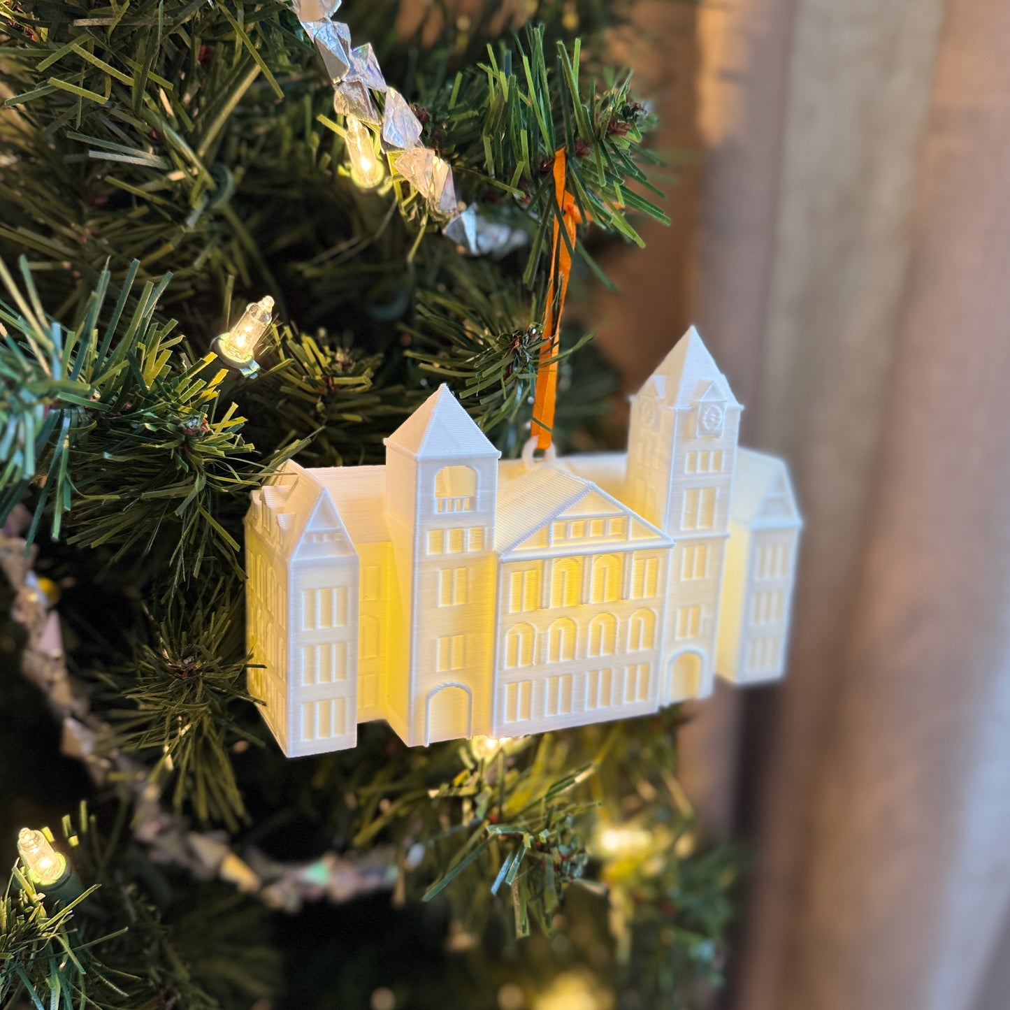 Lighted Auburn University ornament of Samford Hall, shown from a side view on a Christmas tree.