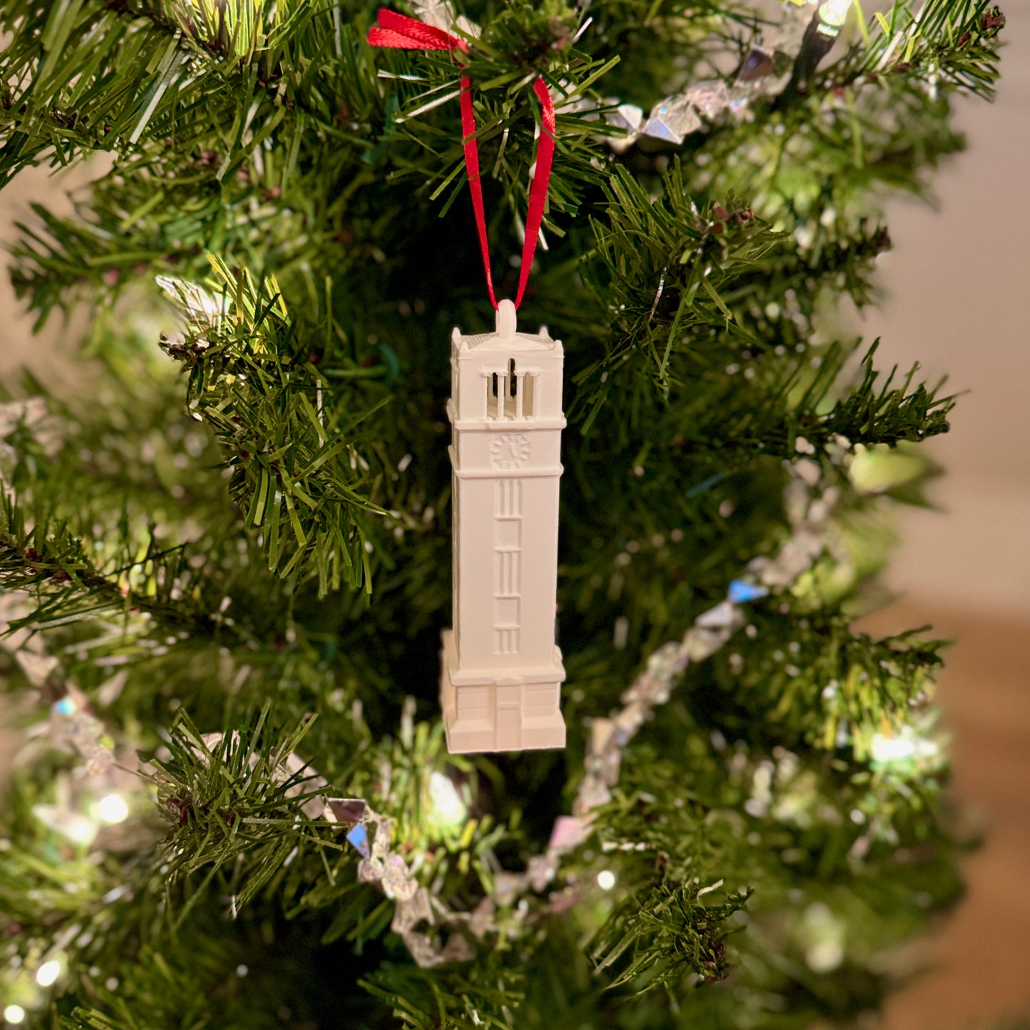 The NCSU ornament designed as the NC State Memorial Tower Building and shown on a Wolfpack tree.
