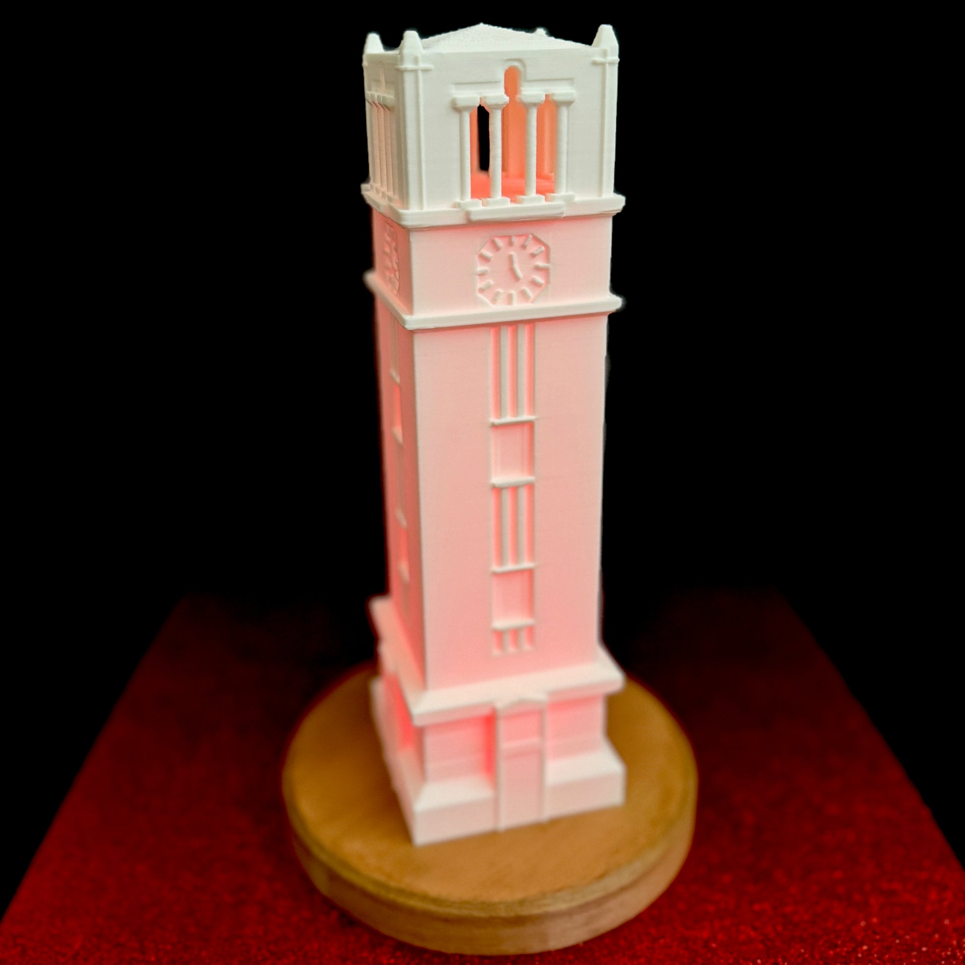 The NC State Bell Tower light, shown against a red background.