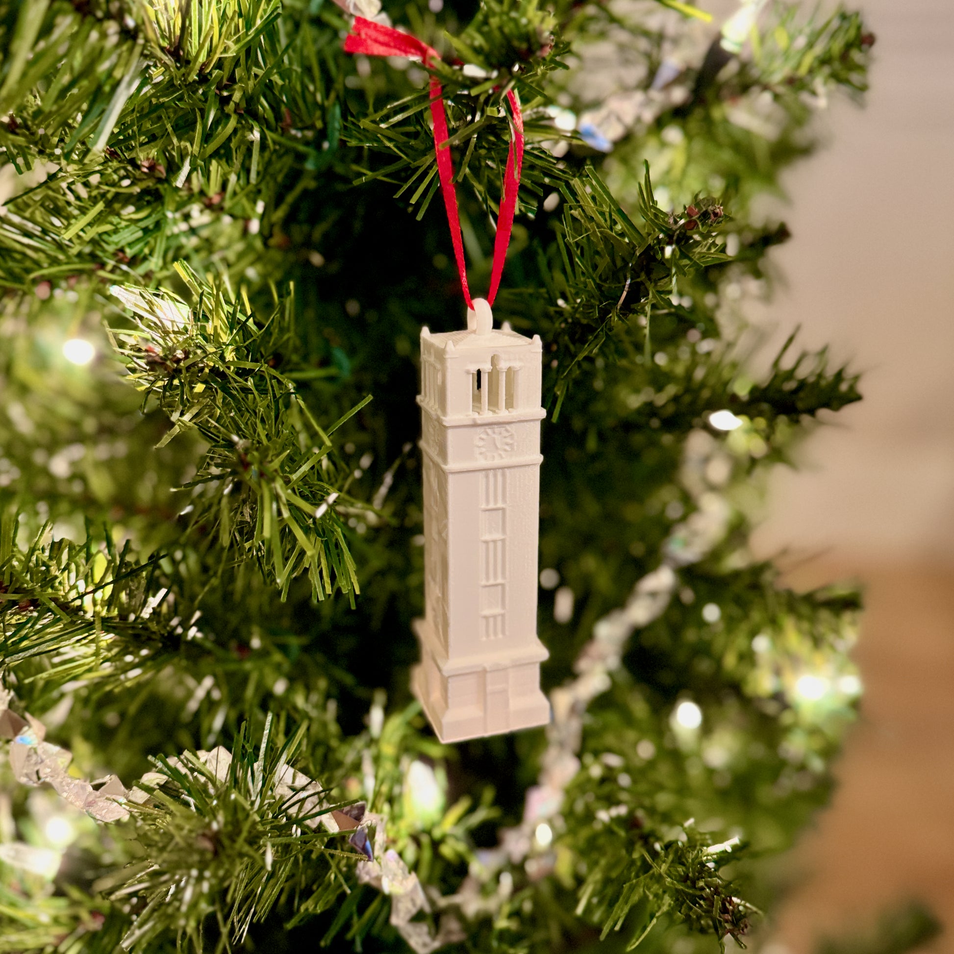 The NC State Christmas ornament of the Bell Tower, shown on a Wolfpack tree.