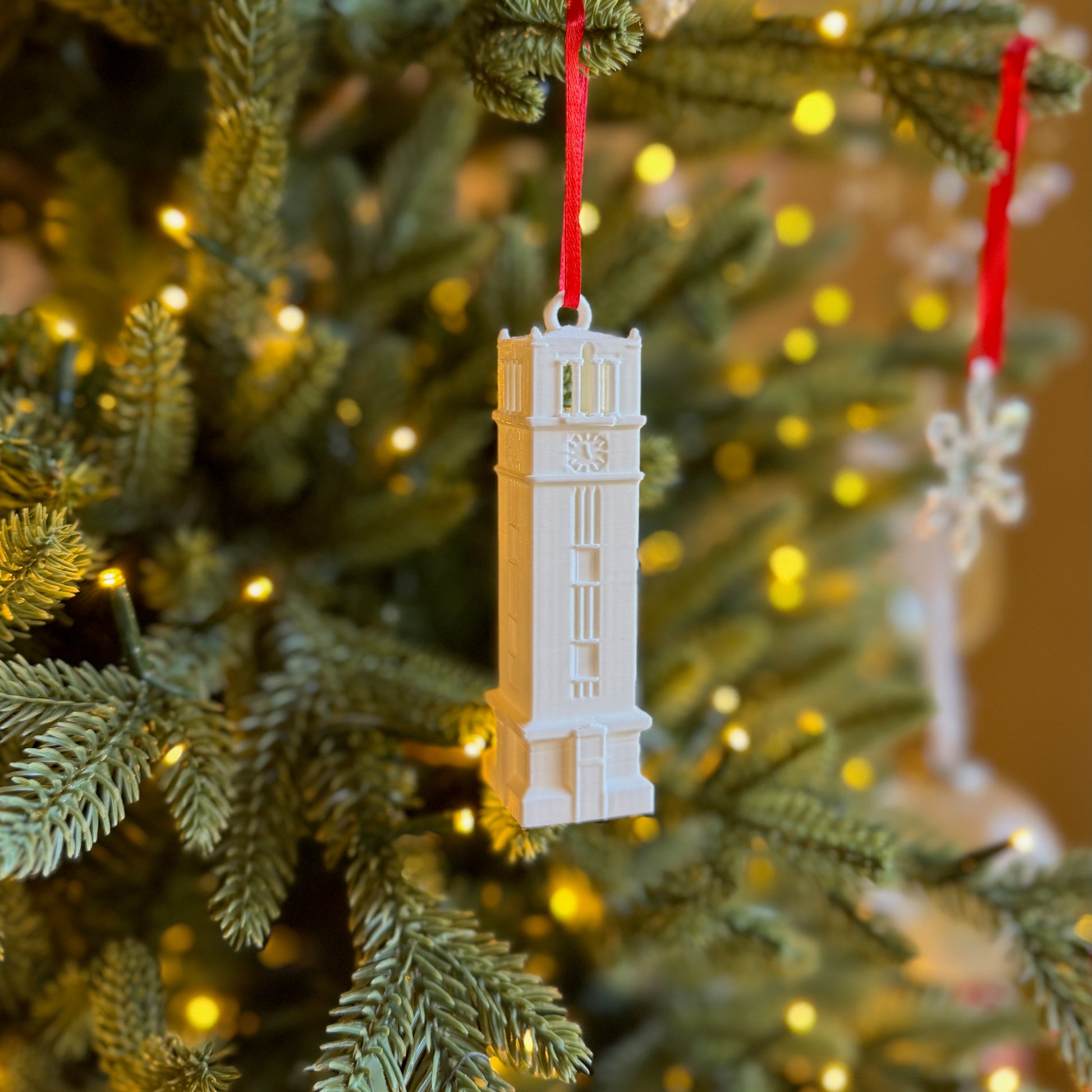 The NC State ornament, designed in honor of the Bell Tower, and shown on a Christmas tree.