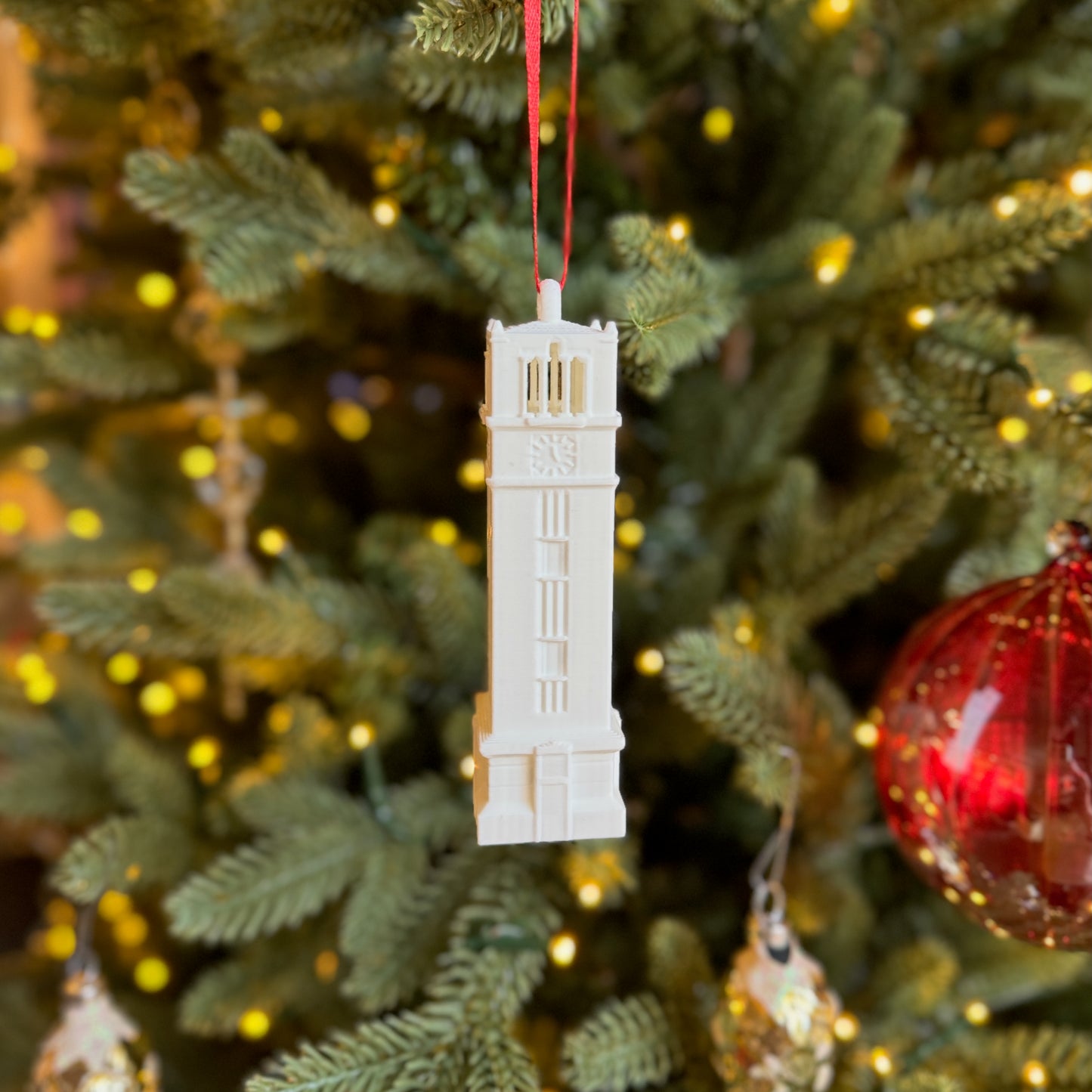 Front view of the NC State keepsake ornament, shown on a Christmas tree.