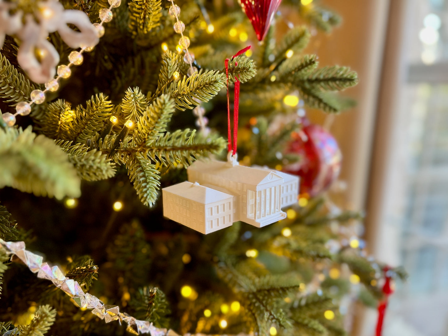 Ole Miss Christmas tree with ornaments, including a small Lyceum building model, in a home setting.