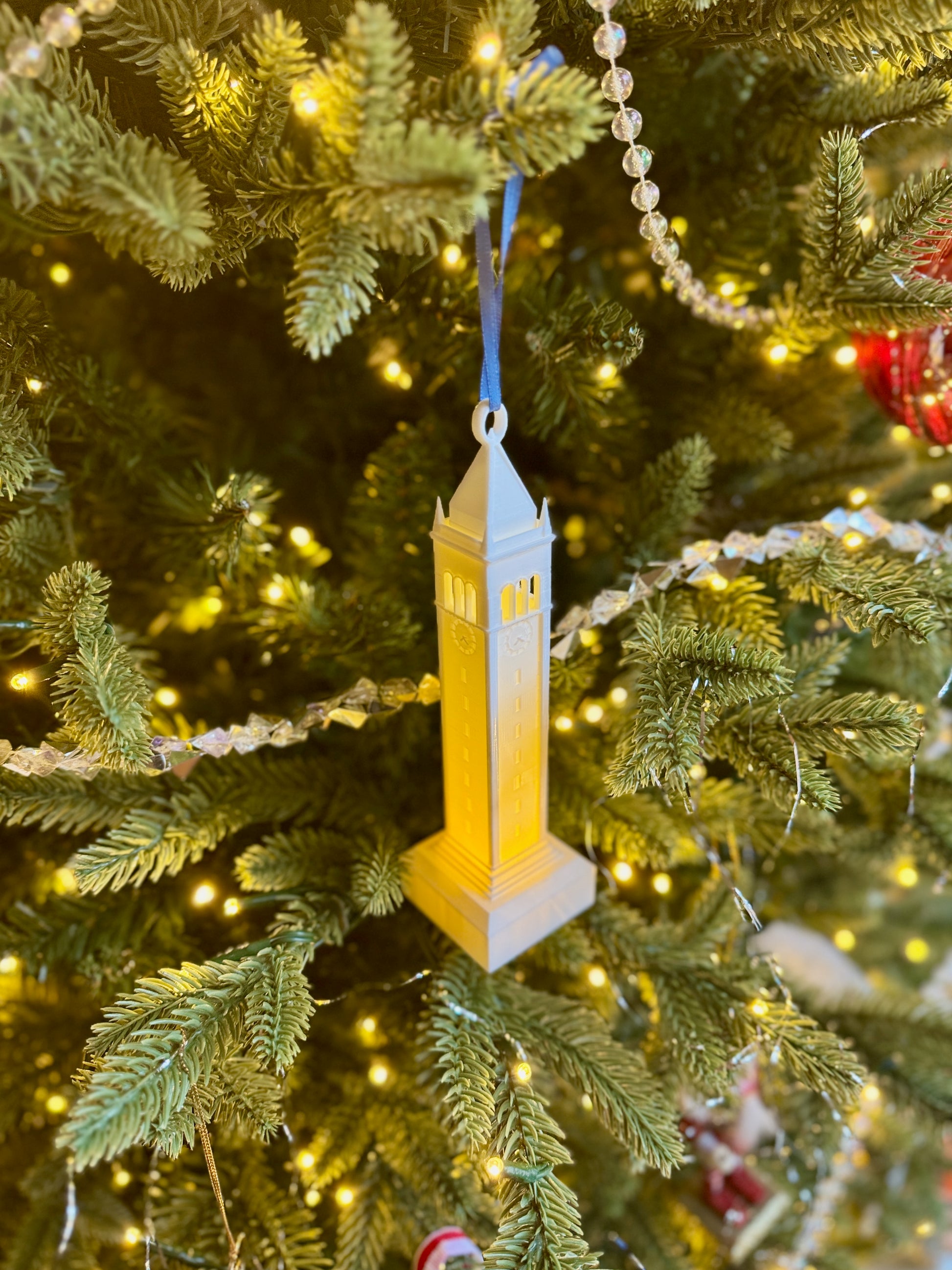 A Sather Tower ornament with LED light, shown on a Christmas tree.