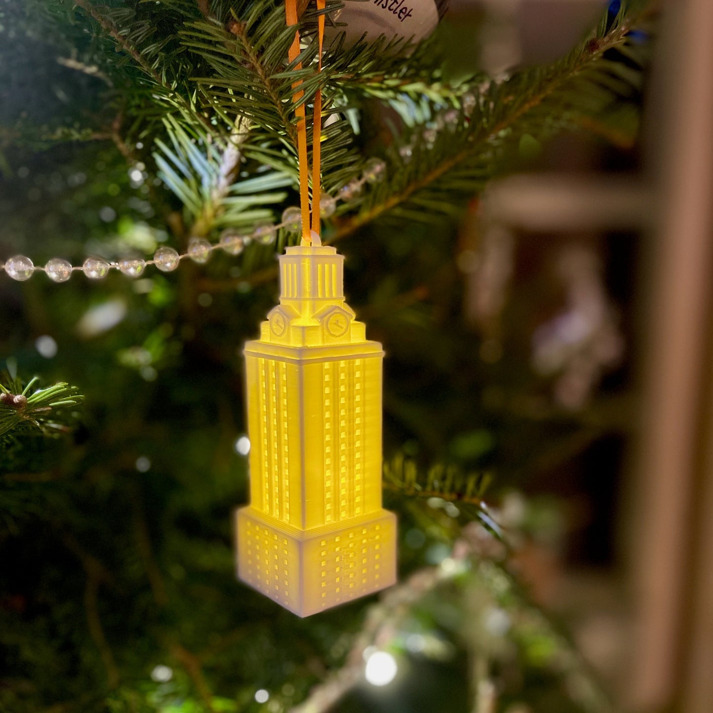 The lighted UT Austin campus ornament, shown on a Christmas tree.