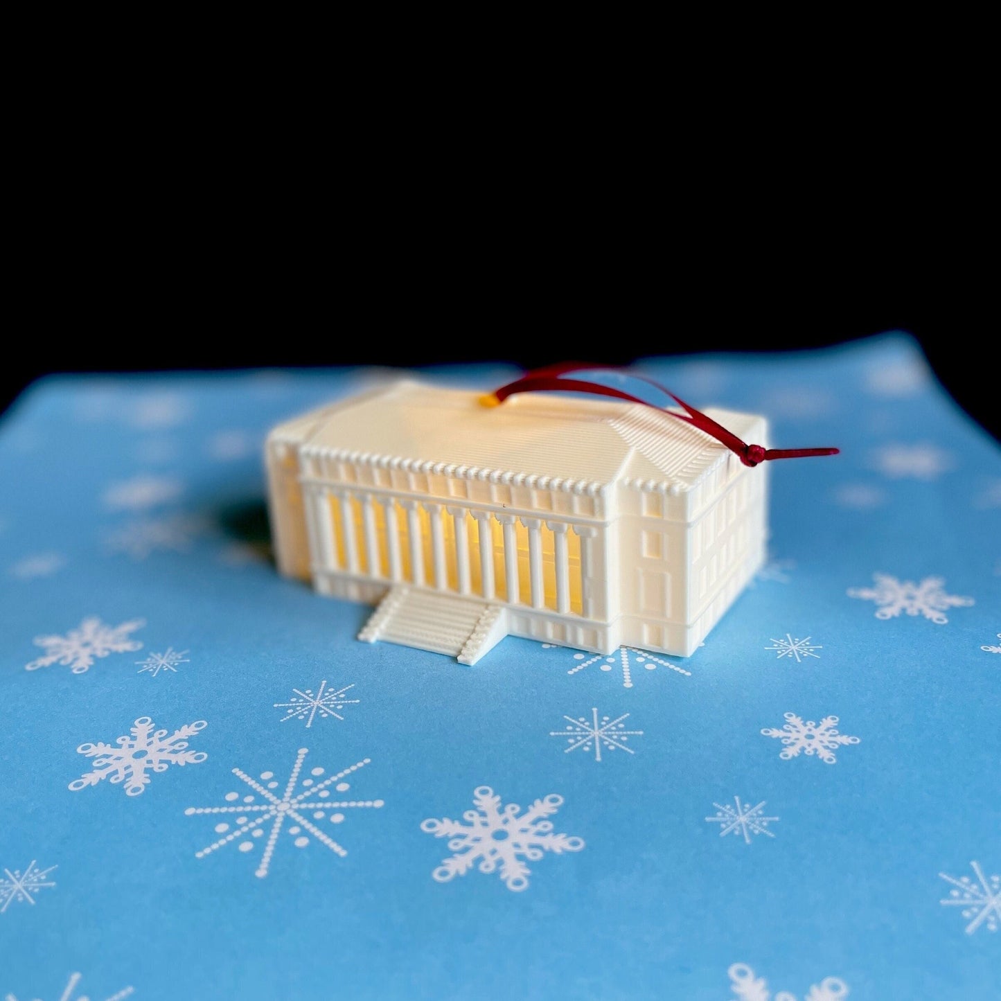 The Texas A&M ornament with light, shown on a blue holiday background.