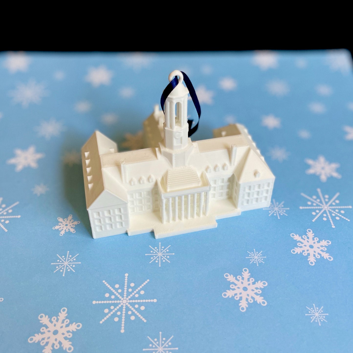 The Penn State Christmas decoration, shown against a blue holiday background.