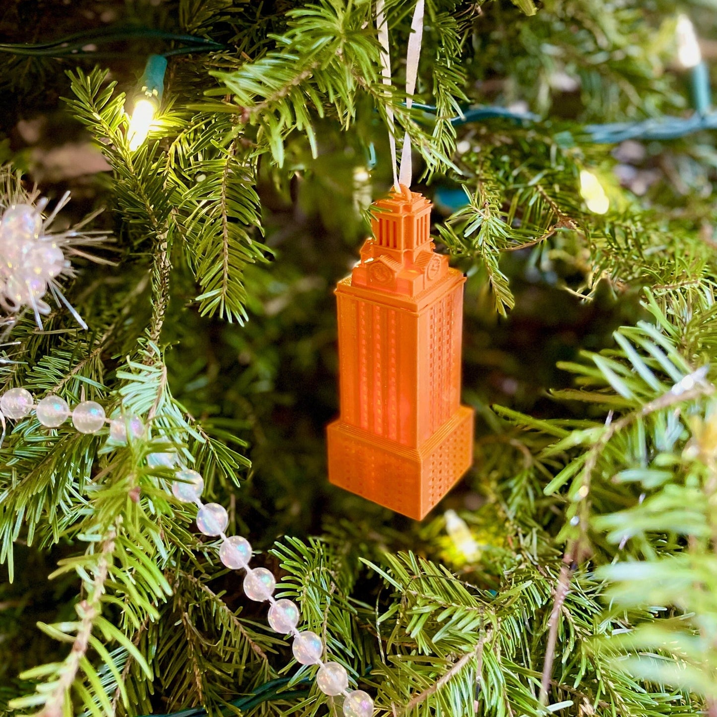 The burnt orange UT Tower ornament, shown on a Christmas tree.