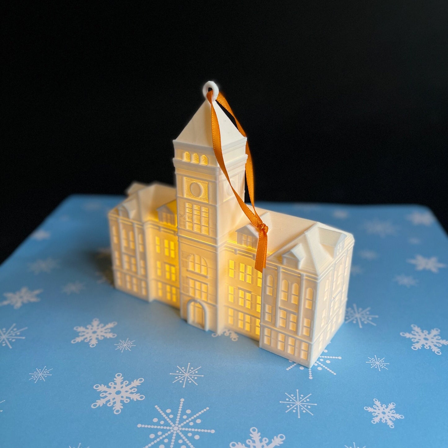 The lighted Clemson ornament, shown against a blue holiday background.