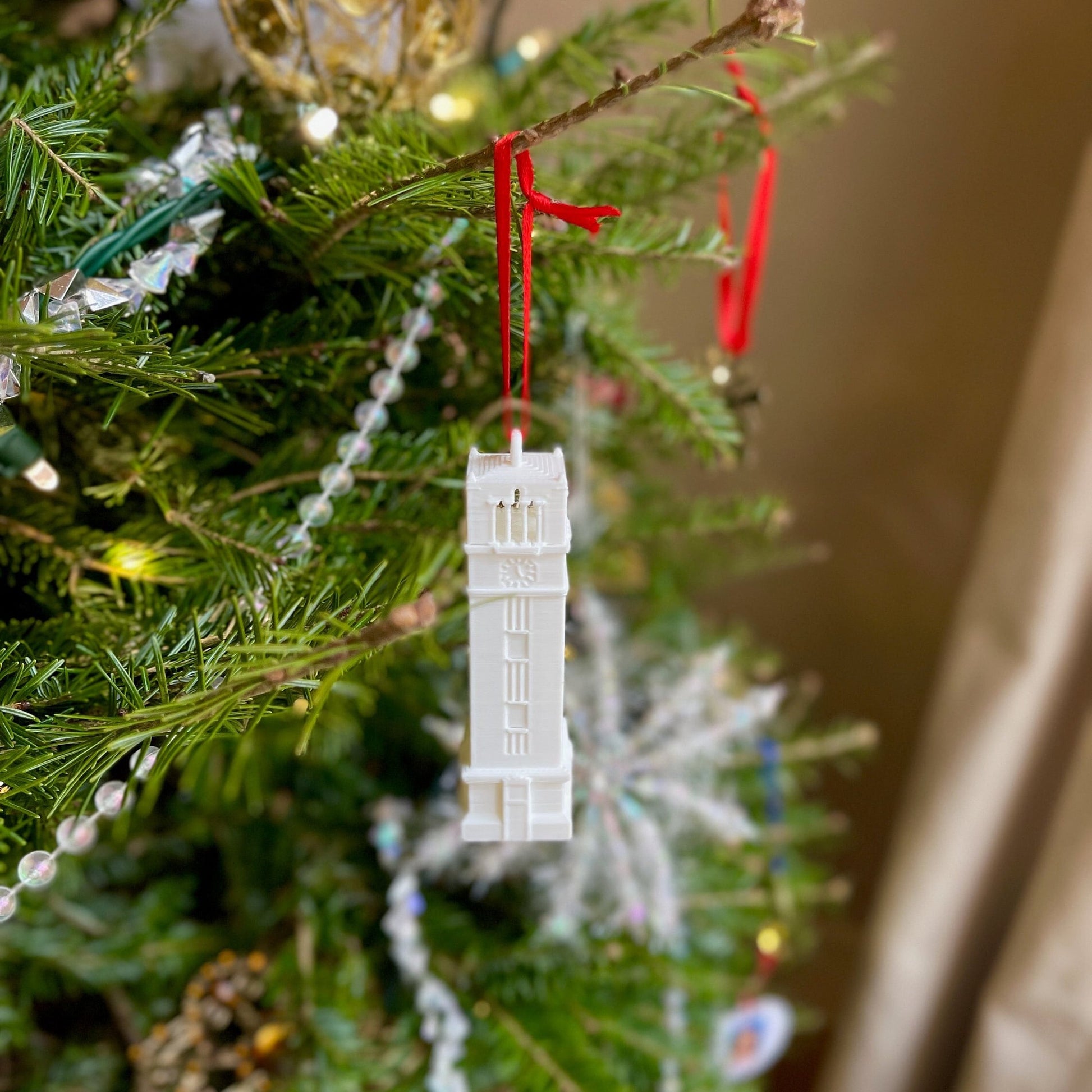 The NC State Bell Tower ornament, shown on a Christmas tree.