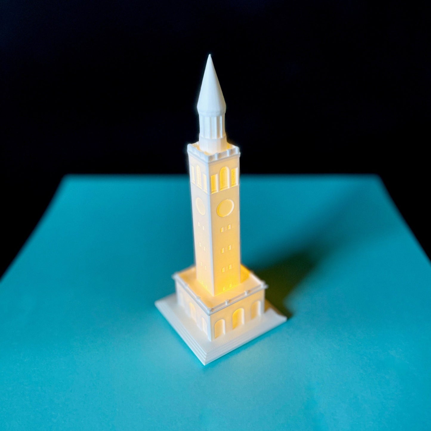 The lighted UNC Tower figurine, shown against a blue background.