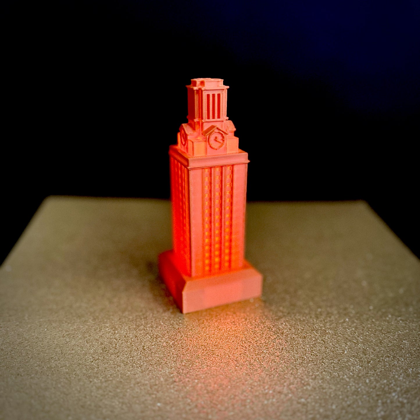 The burnt orange UT Tower light, shown against a gold background.