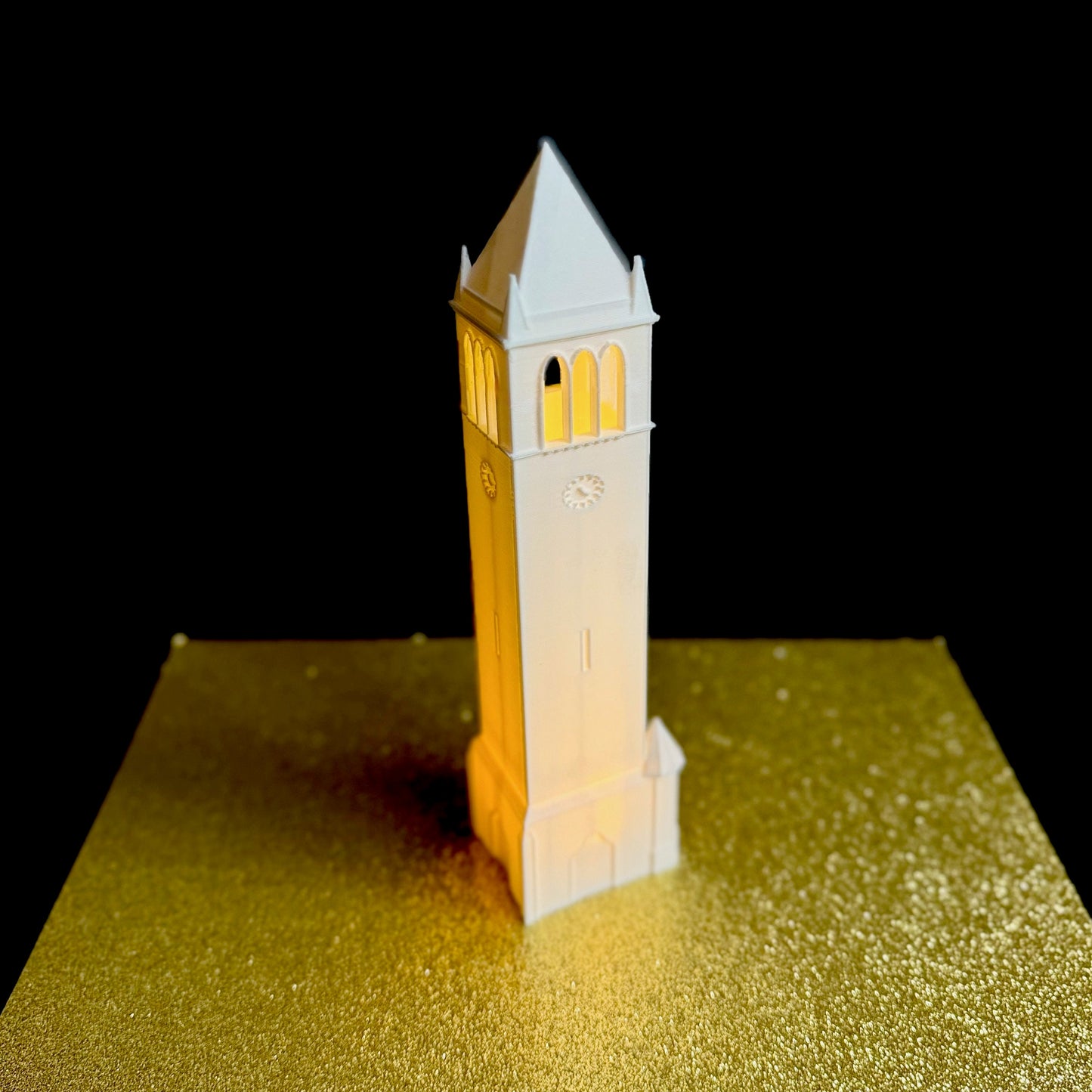 The lighted Iowa State figurine, shown against a gold background.