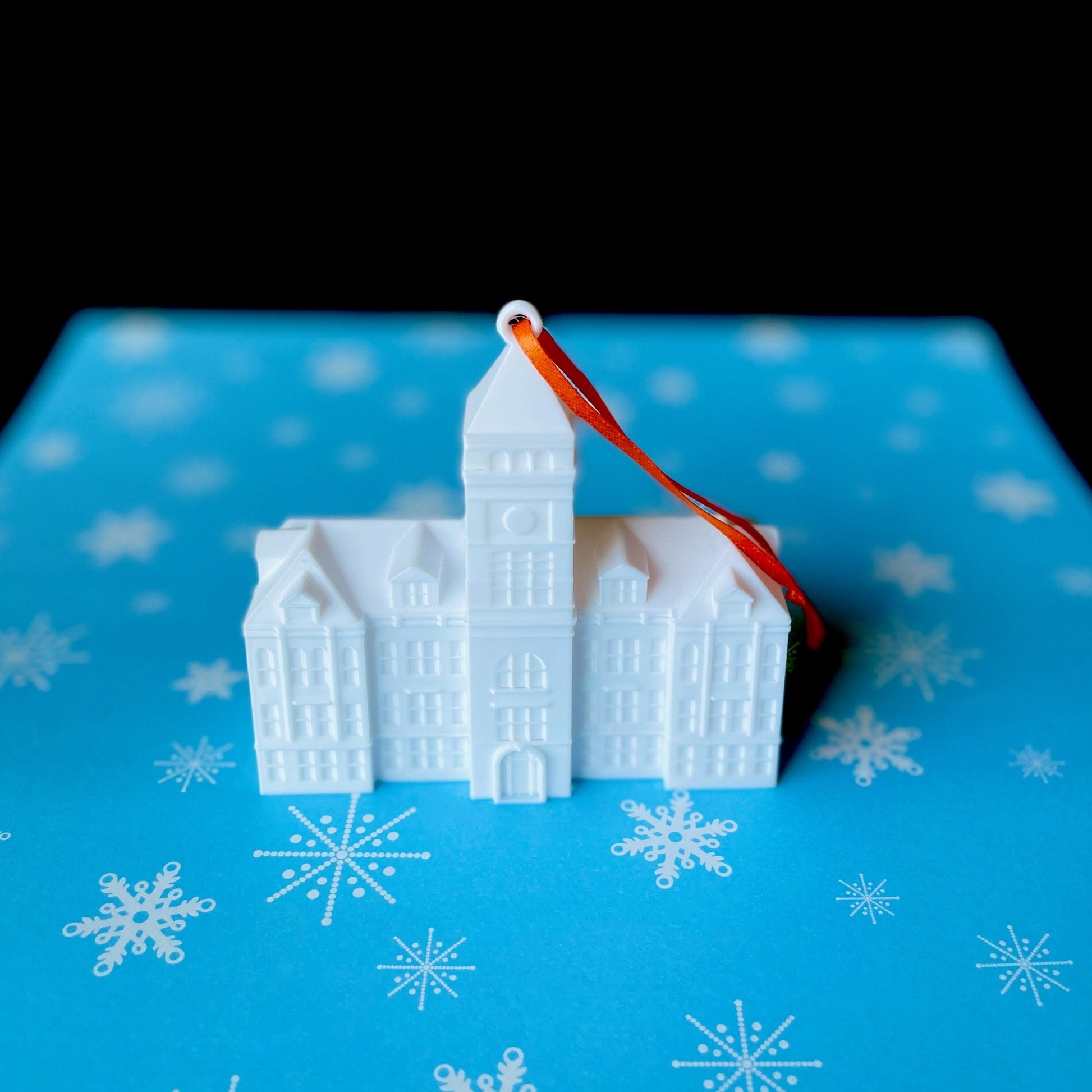 The Tillman Hall ornament from Clemson University, shown against a blue holiday background.