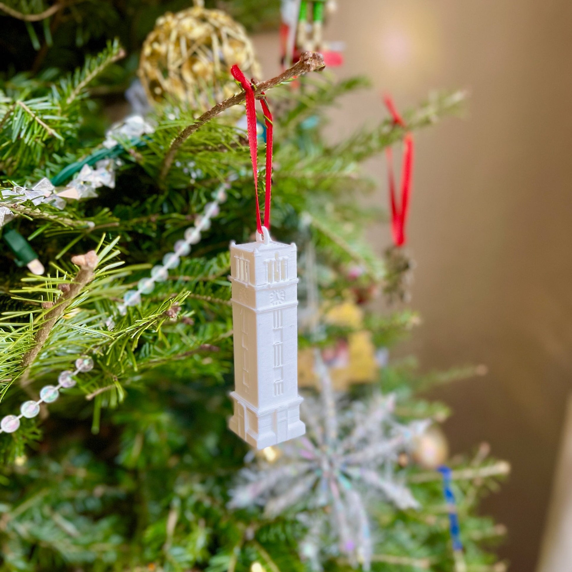 The NC State Tower ornament, displayed on a tree decorated for Christmas.