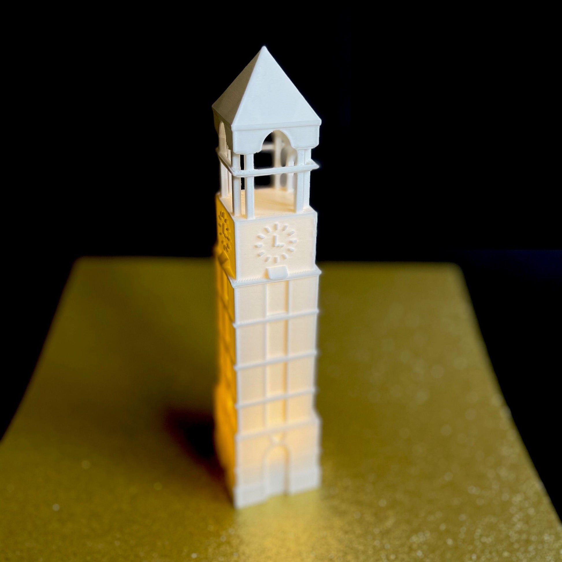 The Purdue keepsake light, shown on a gold background.