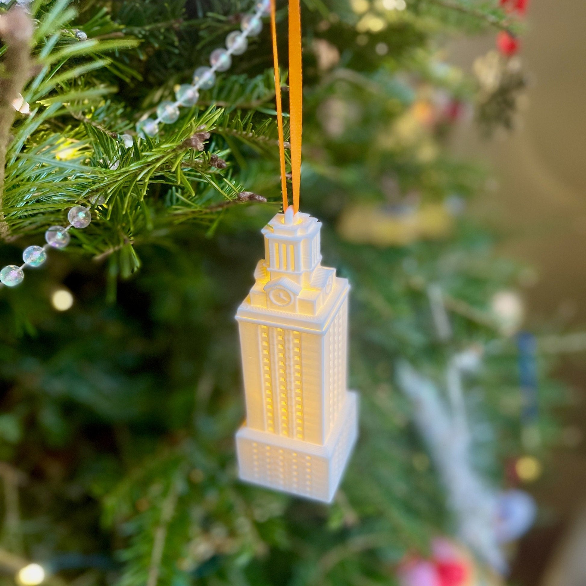 The white UT Tower ornament, shown on a Christmas tree.