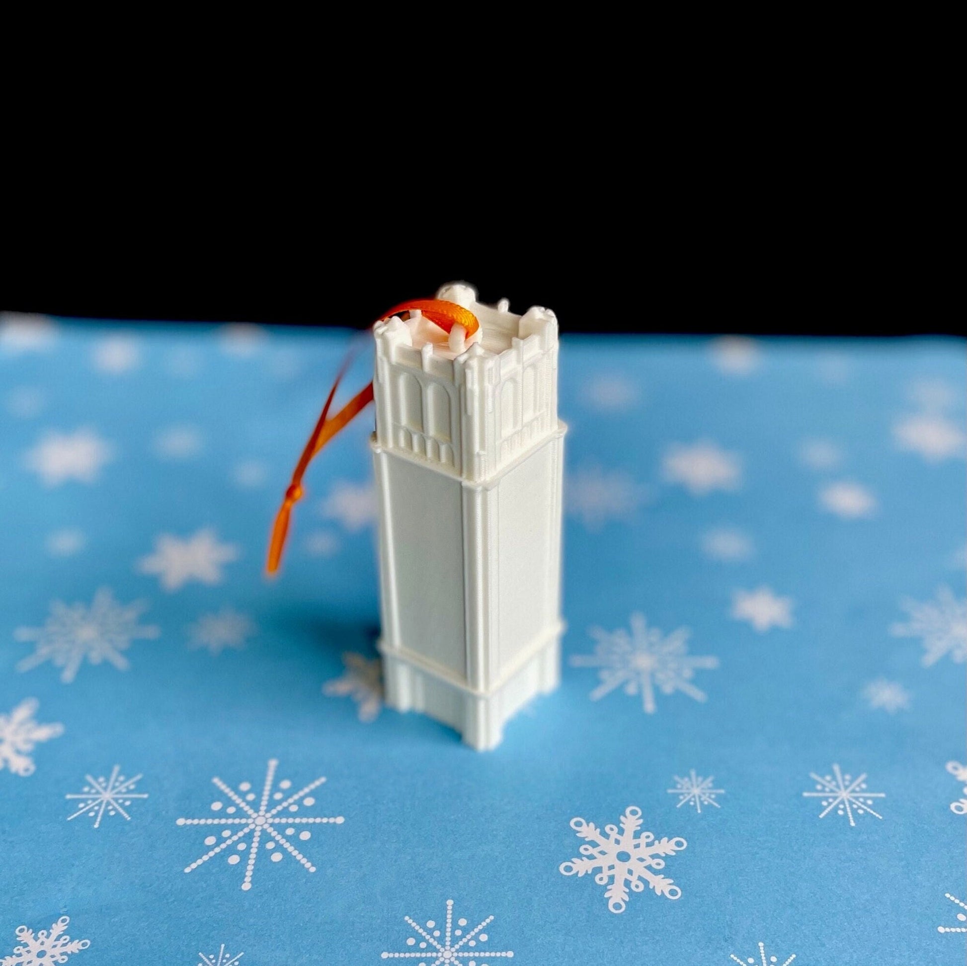 Top view of the University of Florida Century Tower ornament, shown against a blue holiday background.