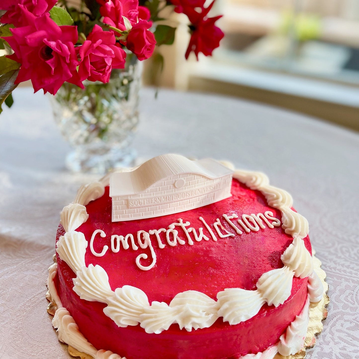 The SMU cake topper figurine, shown on a red SMU graduation cake.