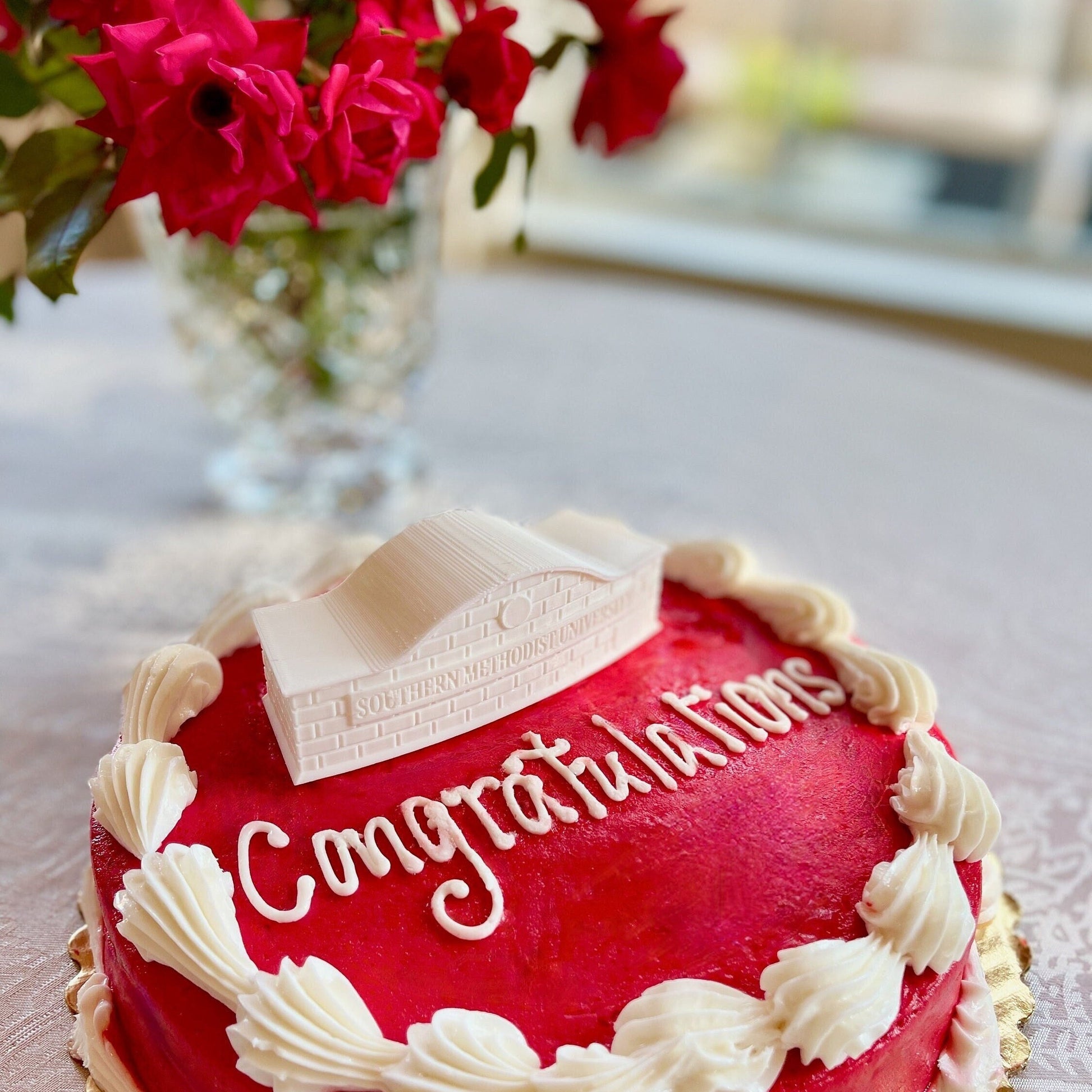 The SMU cake topper, designed to look like the SMU entrance sign, and shown on an SMU graduation cake.