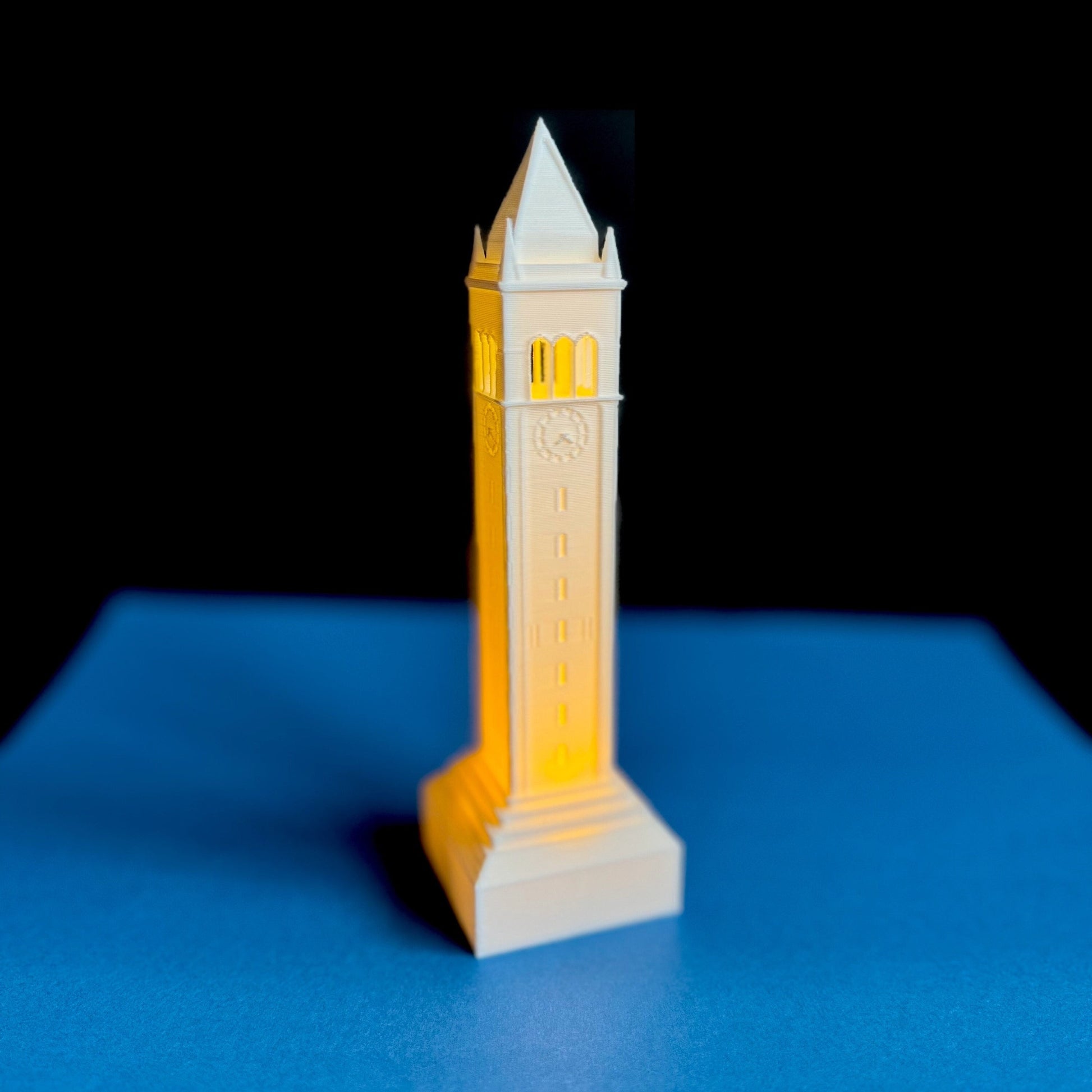 The lighted Berkeley Campanile figurine, shown against a blue background.