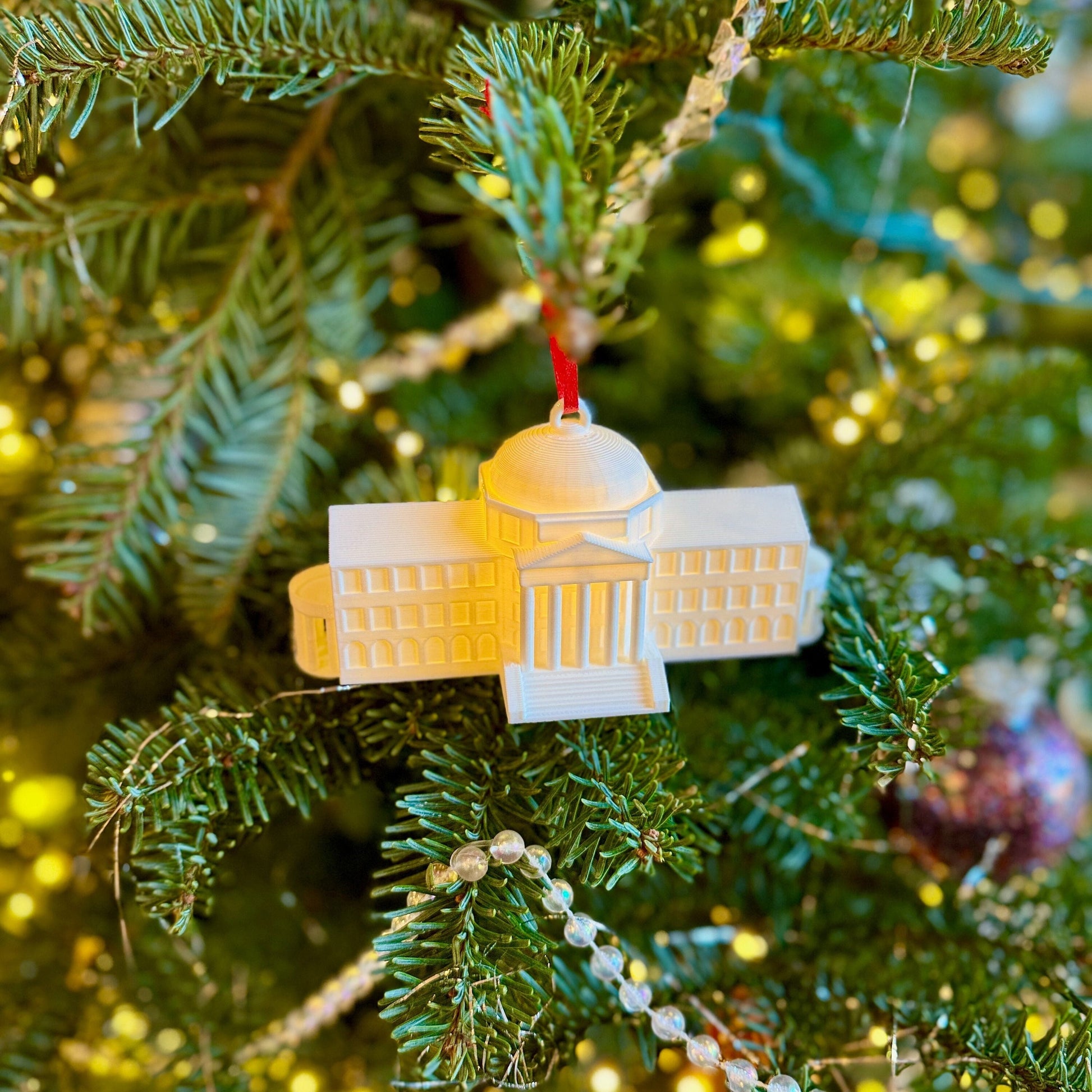 The lighted SMU ornament, designed as a replica of the SMU Dallas Hall and shown on a Christmas tree.