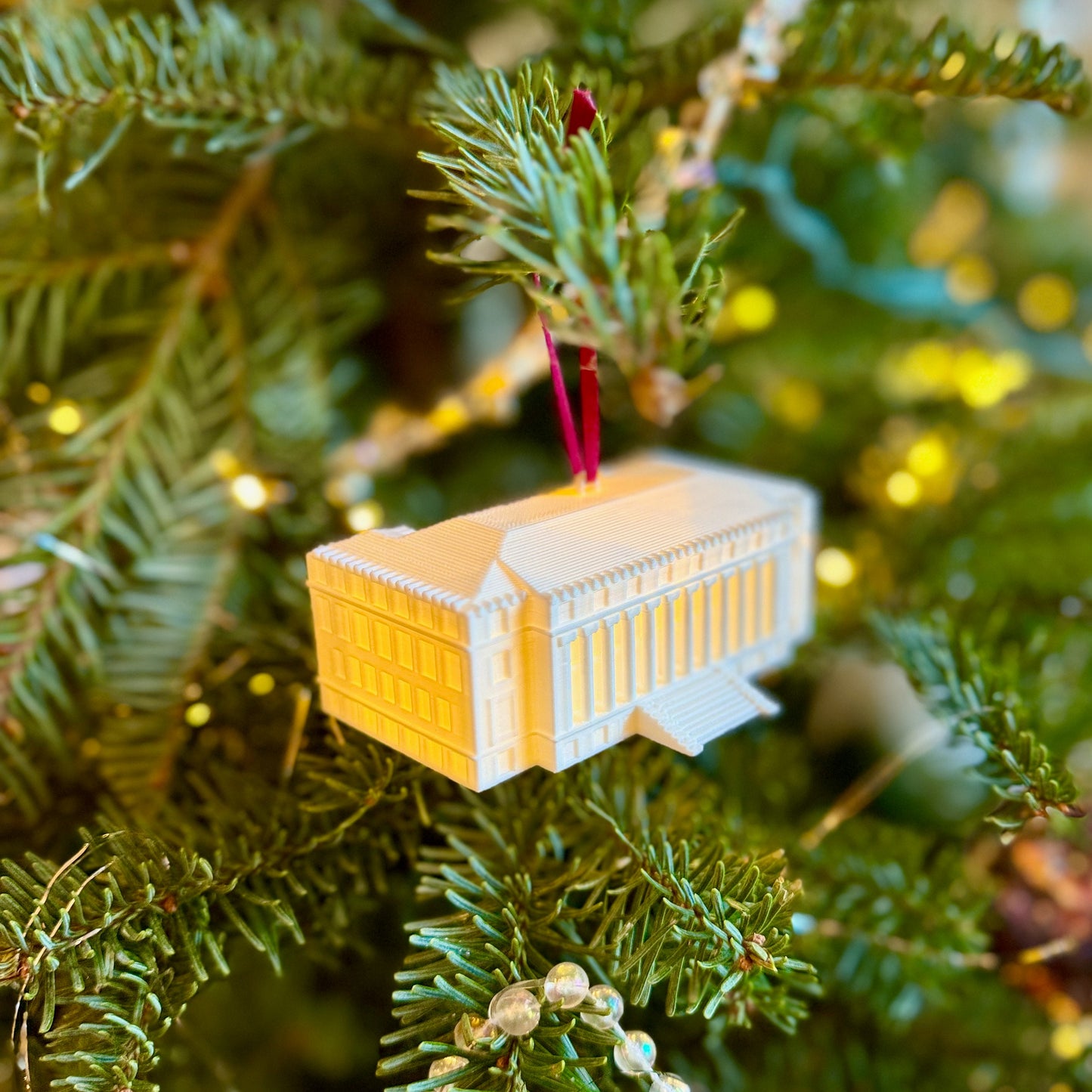 The TAMU Christmas ornament, shown on a Christmas tree and designed in honor of the TAMU Administration Building.