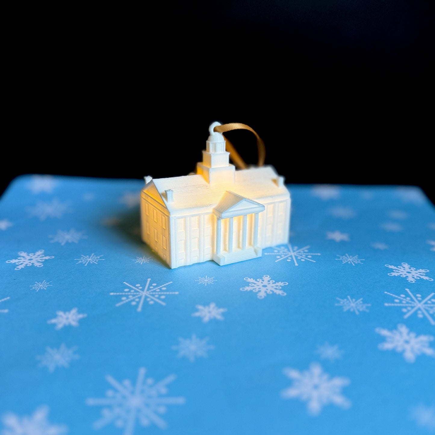 The lighted Iowa Old Capitol ornament, shown against a blue holiday background.