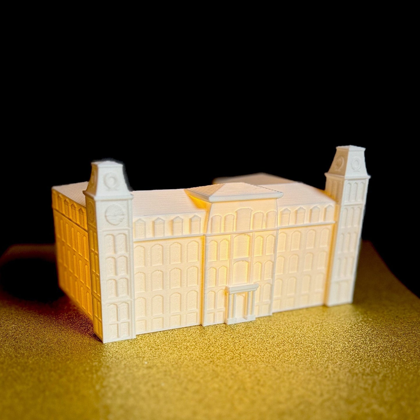 The University of Arkansas Old Main figurine, shown with a soft white light,